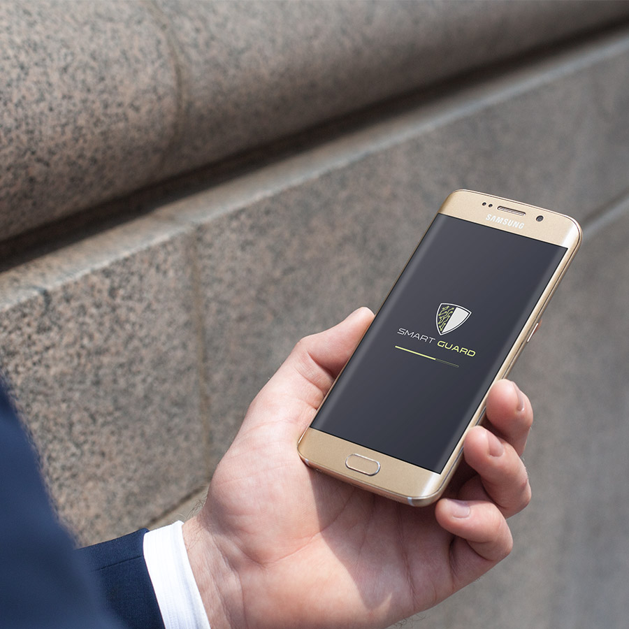 Man holding a smartphone with a screen of a Smartguard logo loading screen